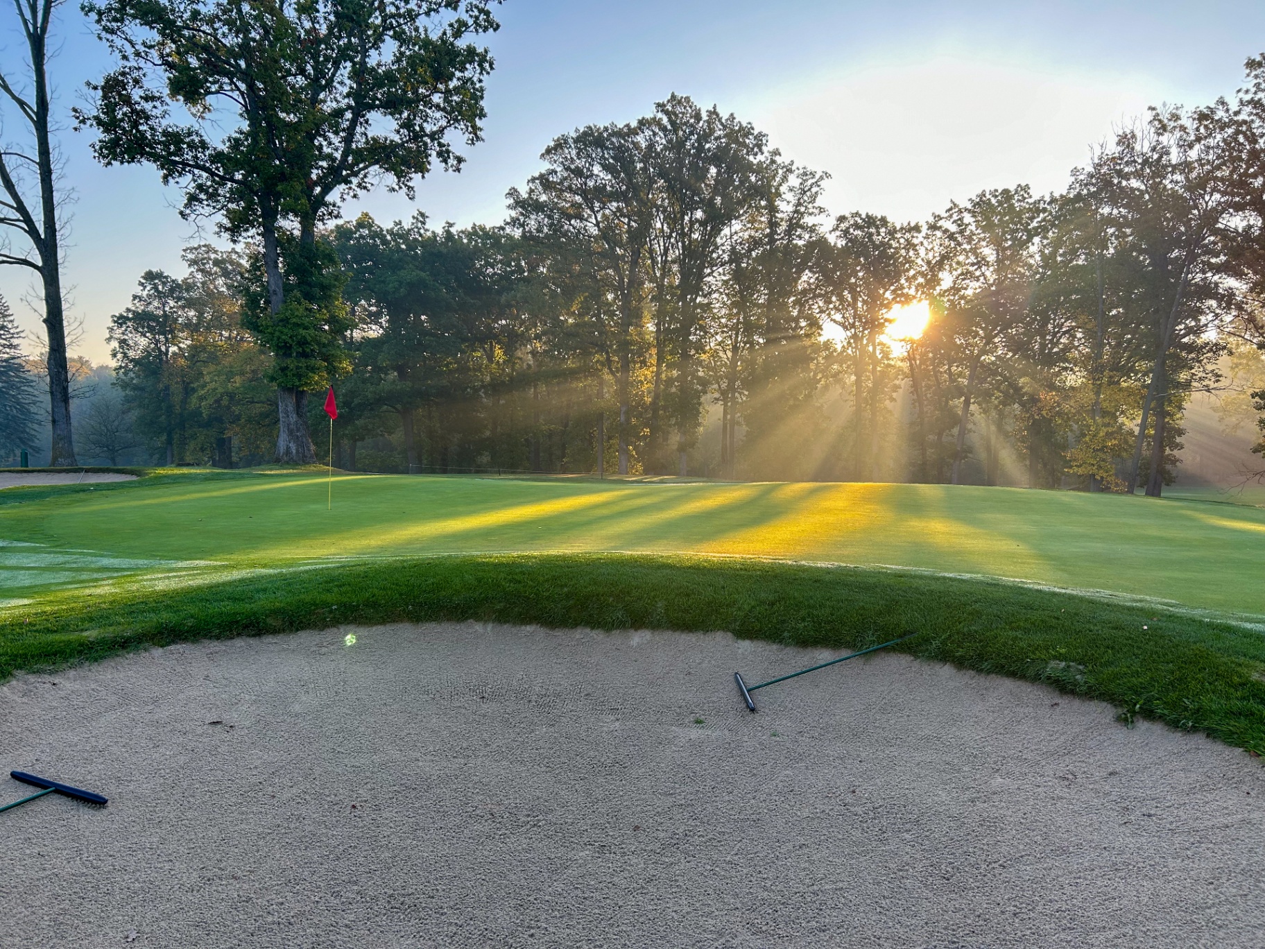 Sunrays breaking through the trees over a green at Brown County Golf Course
